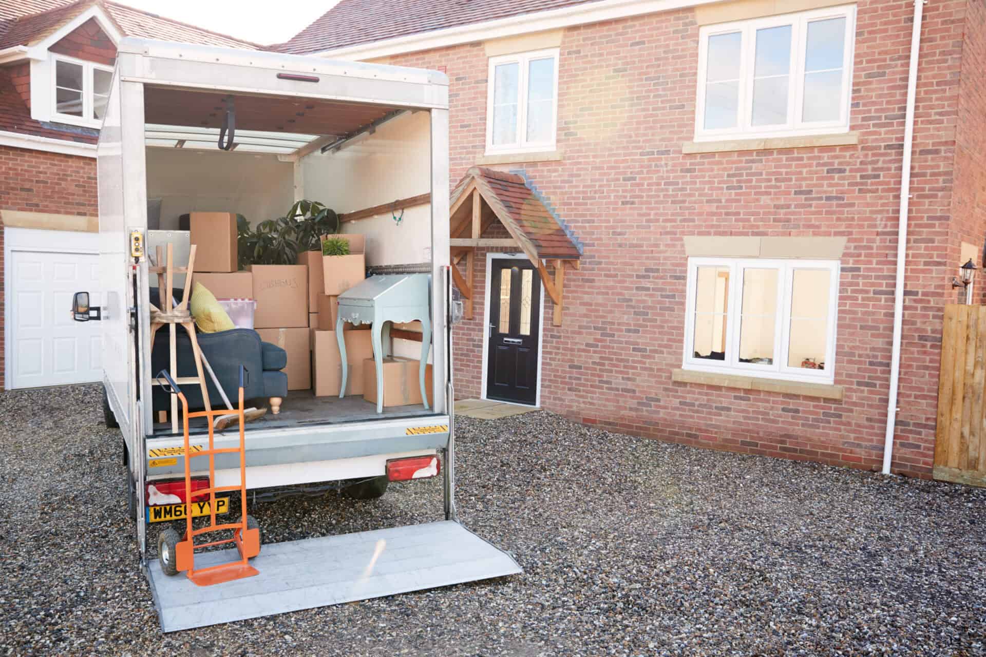 Furniture Removals Truck Waiting To Be Unloaded Outside New Home On Moving Day